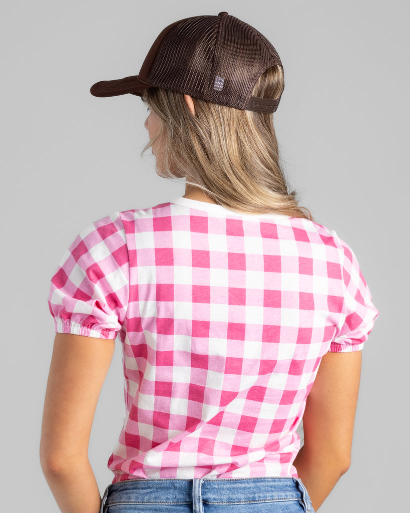 Model wearing a bright pink and white gingham print short sleeve t-shirt.