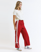 Woman wearing a white t-shirt and red pants with white stripes on a white background