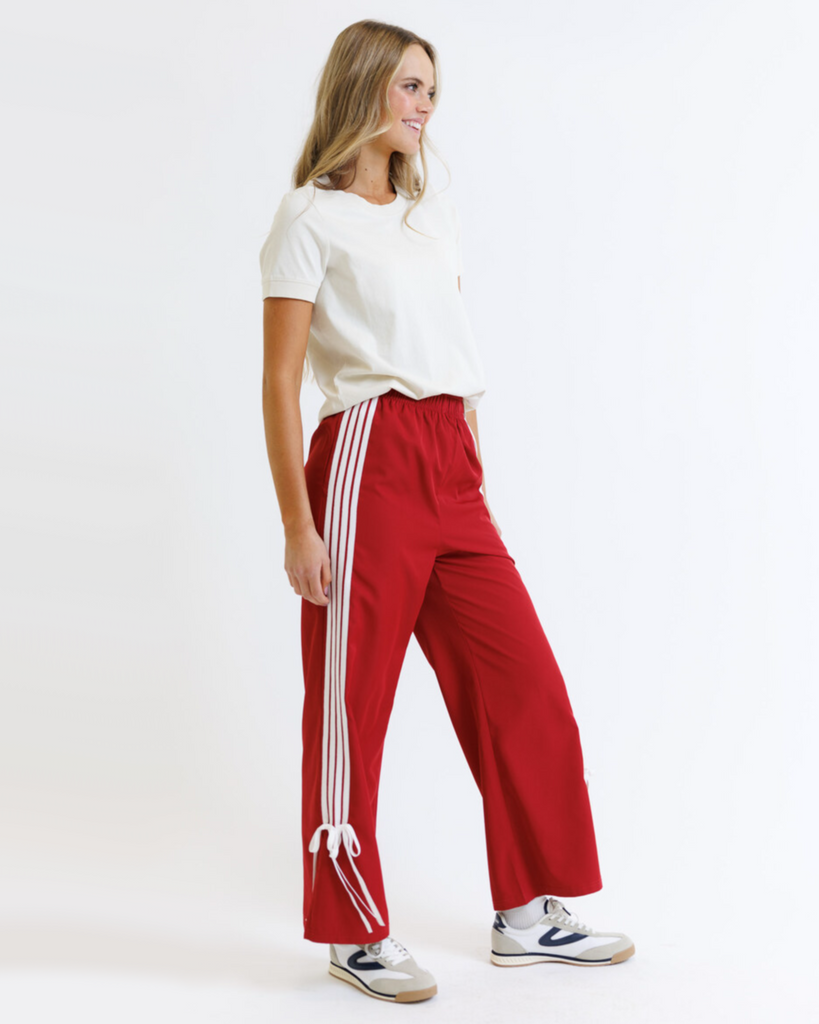 Woman wearing a white t-shirt and red pants with white stripes on a white background