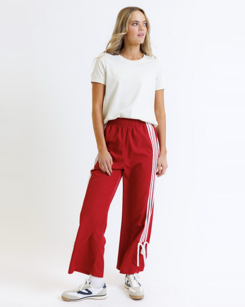 Woman wearing a white t-shirt and red pants with white stripes on a white background