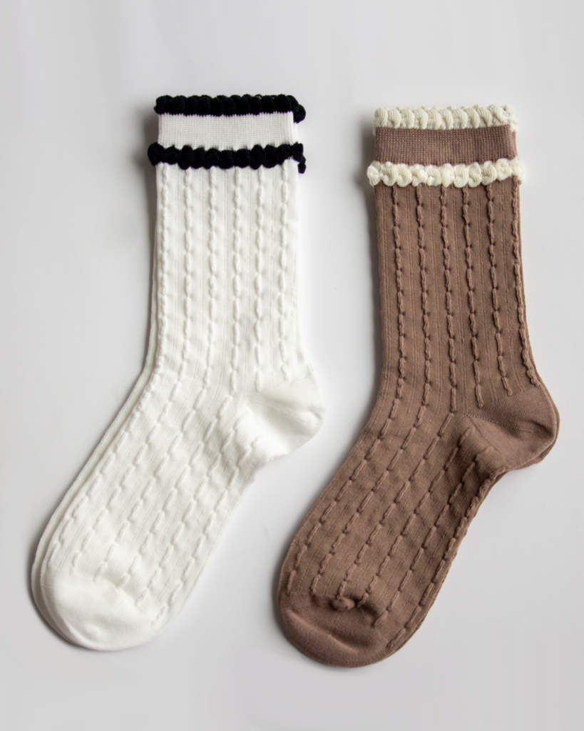Pair of white and brown socks with textured patterns on a light gray background