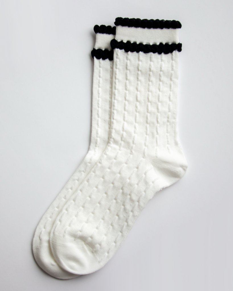 White socks with black ruffle trim on a light gray background