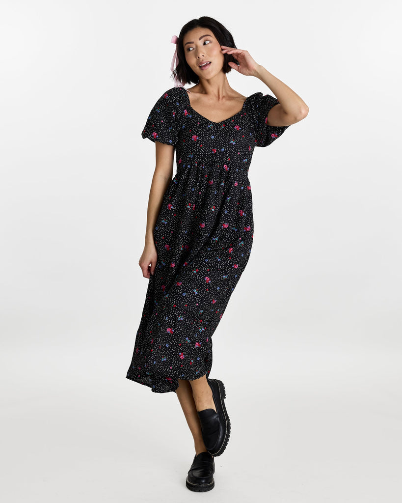 Woman in a short puffed sleeve, midi-length, black with floral print dress