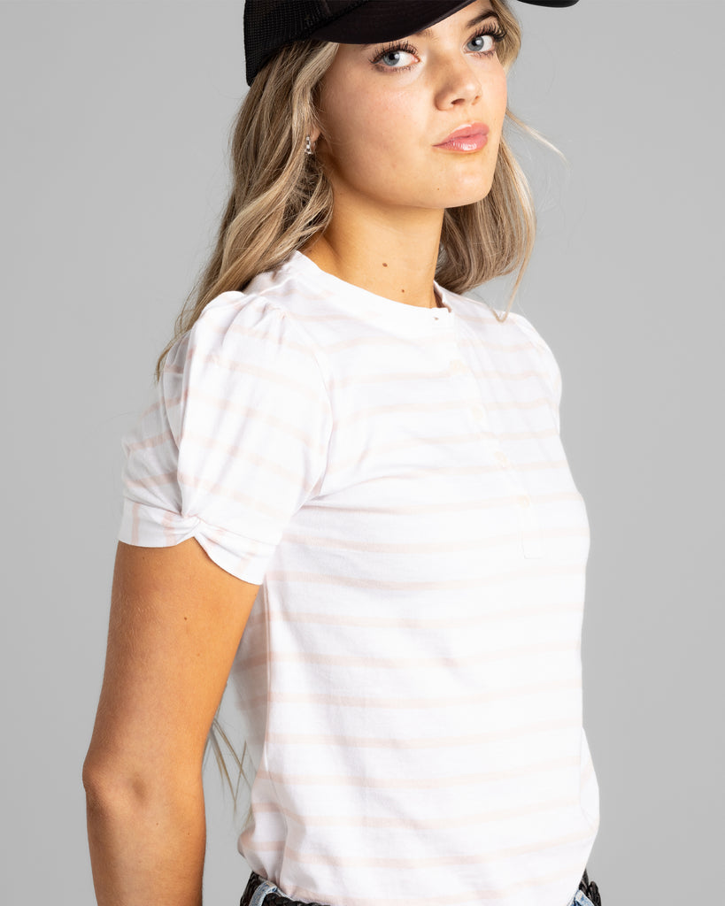 Model wearing a light pink and white striped short sleeve henley tee.