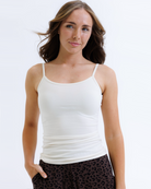 Woman wearing a cream colored layering tank top against a white background