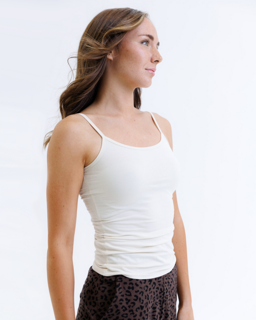 Woman wearing a cream colored layering tank top against a white background