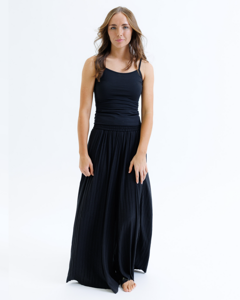 Woman wearing a black layering tank top and black maxi skirt against a white background