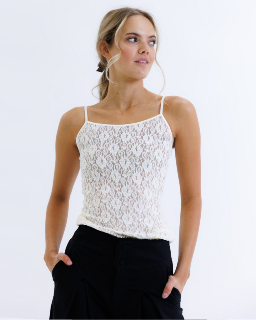 Woman wearing a white lace top and black pants on a white background