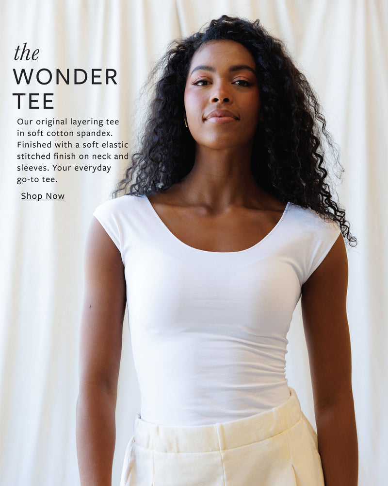 Woman wearing a white t-shirt with promotional text on a plain background