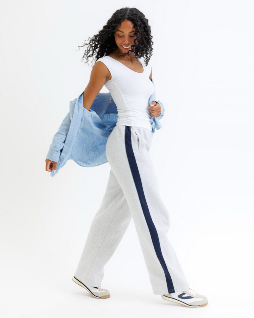 Woman wearing a white layering top and gray pants on a white background