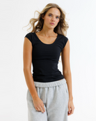 Woman wearing a black layering top and gray sweatpants on a white background