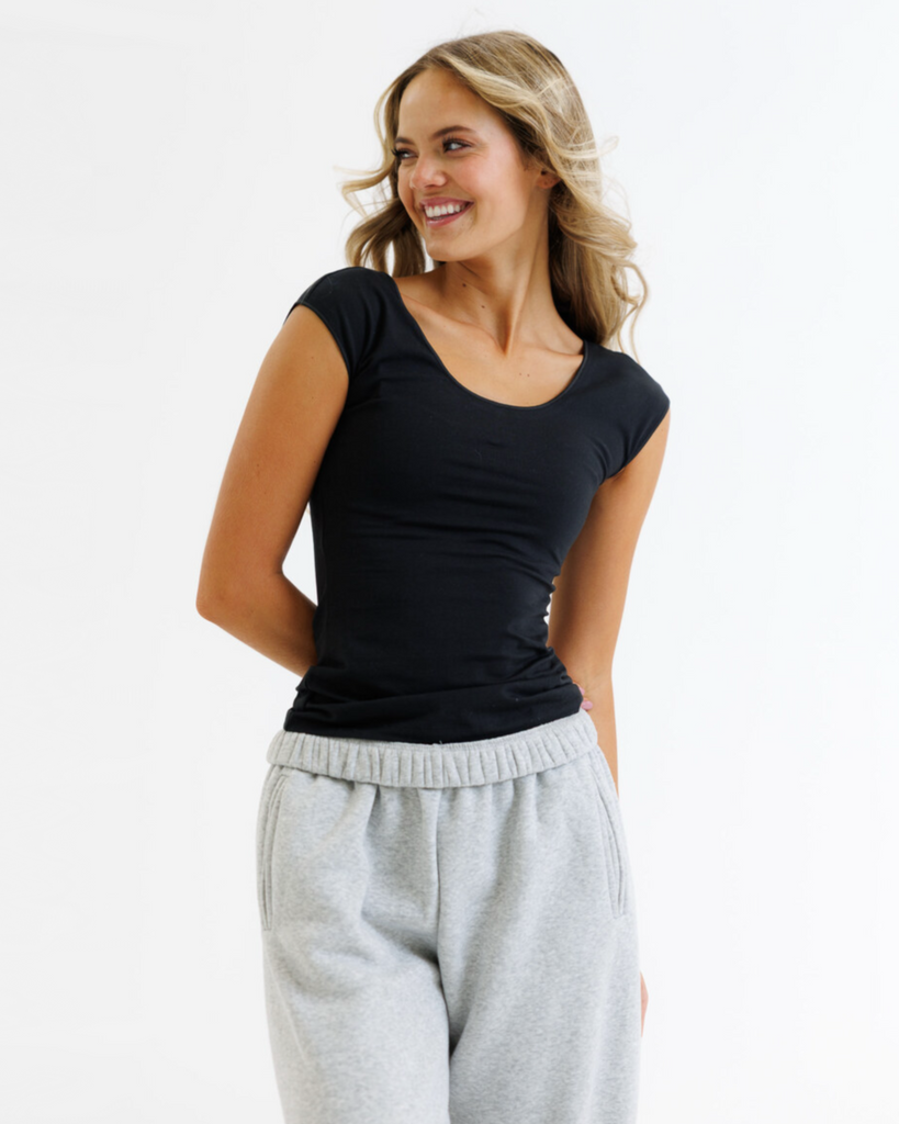 Woman wearing a black layering top and gray sweatpants on a white background