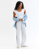 Woman wearing a white layering top with a denim shirt on a white background