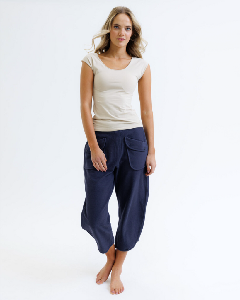 Woman wearing a beige top and navy blue pants on a white background