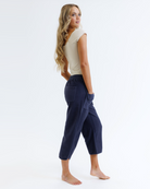 Woman wearing a beige top and navy blue pants on a white background