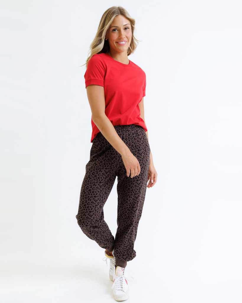 Woman wearing a red t-shirt and leopard print pants on a white background