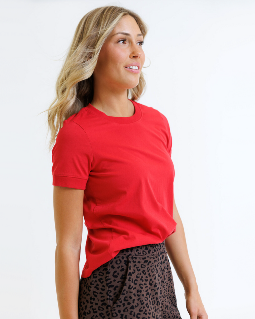 Woman wearing a red t-shirt and leopard print pants on a white background