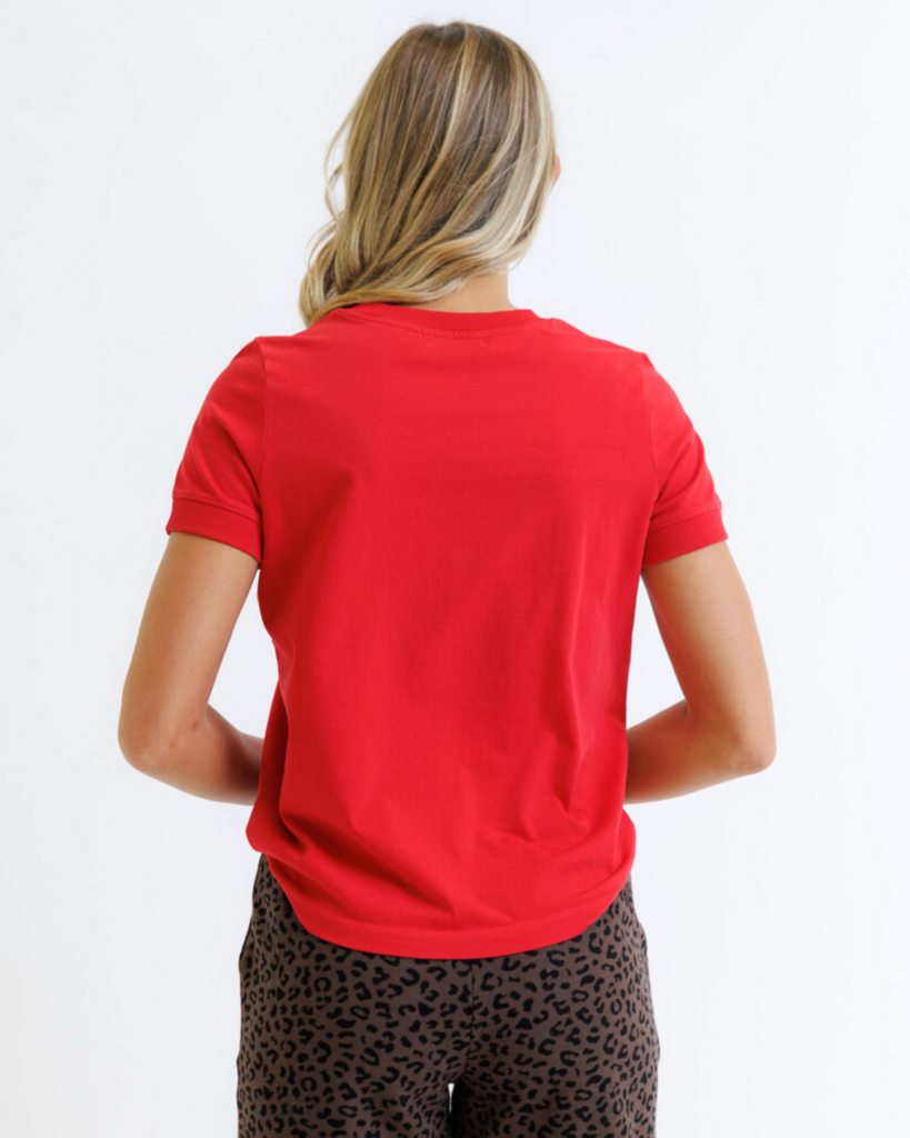 Woman wearing a red t-shirt and leopard print pants on a white background