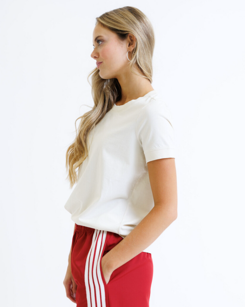 Woman wearing a white t-shirt and red track pants with white stripes on a white background